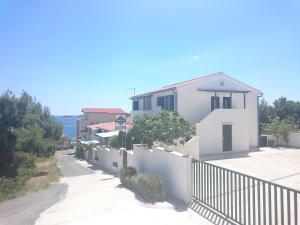 a white house with a fence next to a street at Apartments Riba in Vis