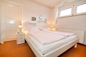 a white bedroom with a bed and two windows at Gästehaus Jacobs in Bliesdorf