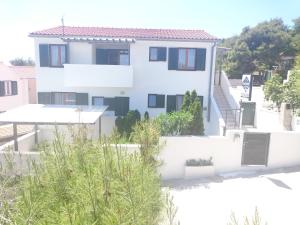 a white house with trees in front of it at Apartments Riba in Vis