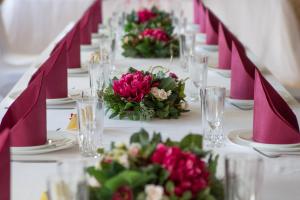 una mesa larga con mesas blancas con flores rosas en Vallery Guest House en Bigauņciems