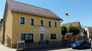 un edificio amarillo con un coche aparcado delante de él en Gasthof Zur Seku, en Neunkirchen am Brand