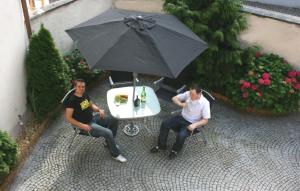 dos hombres sentados en una mesa con un paraguas en Ferienhaus Mainschleife, en Volkach