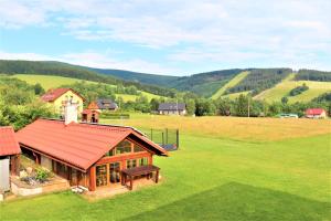 a house with a red roof on a green field at Pension Kohler in Deštné v Orlických horách