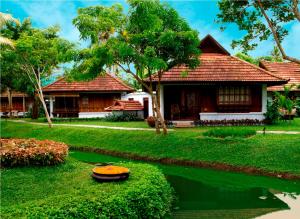 une maison avec un étang en face de celle-ci dans l'établissement Kumarakom Lake Resort, à Kumarakom