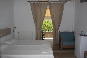 a bedroom with two beds and a chair and a window at Villa Fotis in Ligia