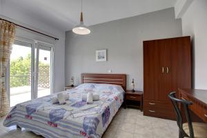 Schlafzimmer mit einem Bett, einem Schreibtisch und einem Fenster in der Unterkunft Istira in Posidi
