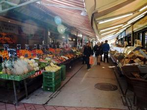 un gruppo di persone che camminano in un mercato con frutta e verdura di Hotel Terminus a Vienna