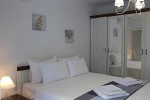 a white bedroom with a bed and a mirror at Blue4Aqua Apartments in Kavála