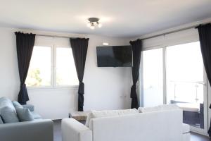 a living room with two white couches and a flat screen tv at Blue4Aqua Apartments in Kavála