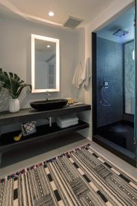 a bathroom with a sink and a large mirror at Mykonos Blanc - Preferred Hotels & Resorts in Ornos