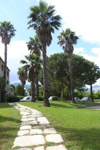 um caminho de pedra num parque com palmeiras em Cors'Hotel em Biguglia