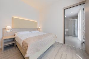 biała sypialnia z dużym łóżkiem i lustrem w obiekcie Hotel Delfino Venezia Mestre w Mestre