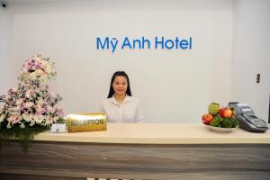 a woman standing behind a counter with a box of my am hotel at My Anh 120 Central Saigon Hotel Ben Thanh Market in Ho Chi Minh City