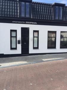 a white building with a black door and windows at appartementen zeespiegel in Zandvoort