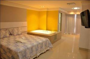 a bedroom with a bed and a bath tub at Brisa Tower Hotel in Ceilândia
