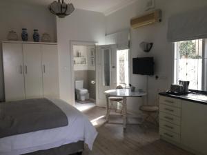 a bedroom with a bed and a table and a bathroom at The Good Life in Durban