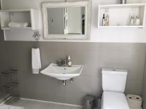 een badkamer met een wastafel, een toilet en een spiegel bij The Good Life in Durban