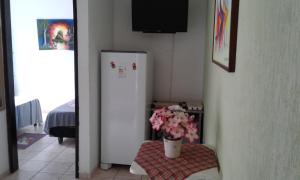 Cette chambre comprend un réfrigérateur blanc et une table avec des fleurs. dans l'établissement Pousada Suites das Galinhas, à Porto de Galinhas