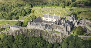 an old castle on top of a hill with trees at Wallace View Apartment in Stirling