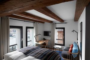 a bedroom with a bed and a desk and windows at 71 Nyhavn Hotel in Copenhagen