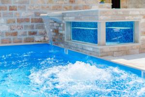 a swimming pool with a water fountain at Luxury house David with heated pool, jacuzzi and sauna in Nerežišće