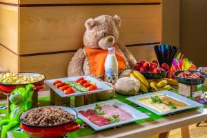 a teddy bear sitting next to a table with food at Dráva Hotel Thermal Resort in Harkány