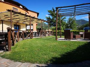 un patio con mesas, sillas y un campo de césped en La Cascina Camere, en Agerola