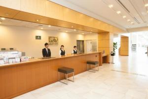 tres personas de pie en un mostrador en el vestíbulo en Hotel Mielparque Kumamoto, en Kumamoto