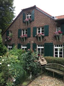 a building with flowers and a bench in front of it at Ferienwohnung auf dem Sturmhof in Grefrath