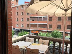 einen Balkon mit 2 Tischen und einem Sonnenschirm in der Unterkunft Pensión Zeus in Barakaldo