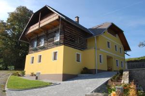una gran casa amarilla con techo de madera en Urlaub am Zechnerhof, en Straßburg in Kärnten