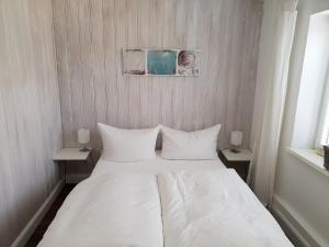 a white bed in a small room with two tables at Budget in Westerland