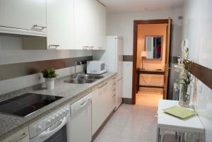 コルドバにあるApartamento céntrico con parking privadoの白いキャビネット、シンク、テーブル付きのキッチンが備わります。