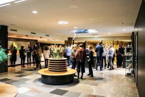 una multitud de personas de pie en un vestíbulo con un jarrón de flores en Hotel C Stockholm, en Estocolmo