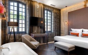 - une chambre d'hôtel avec un lit et une baignoire dans l'établissement Boutique Hôtel des Remparts & Spa, à Aigues-Mortes