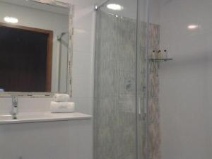 a bathroom with a shower with a sink and a mirror at Guest House A&z in Espinho