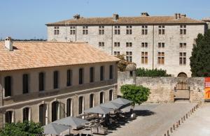 a building with tables and chairs in front of a building at Boutique Hôtel des Remparts & Spa in Aigues-Mortes