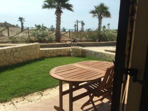 une table et une chaise en bois sur une terrasse avec des palmiers dans l'établissement Marina di Cala del Sole, à Licata