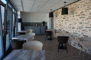 a restaurant with wooden tables and chairs and a brick wall at Hôtel Saint-Roch, The Originals Relais in Saint-Ybard