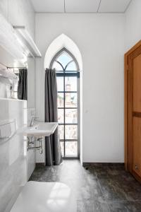 baño blanco con lavabo y ventana en Piano Apartments, en Kaunas