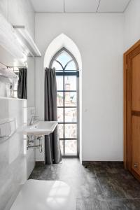 a white bathroom with a sink and a window at Piano Apartments in Kaunas