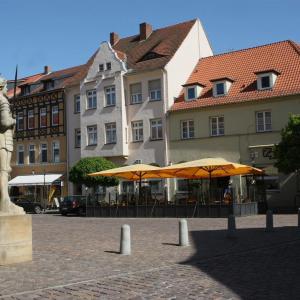 two yellow umbrellas on a street in front of buildings at Hotel-Cafe am Rathaus in Gardelegen