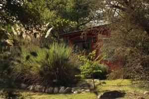 a red house in the middle of a garden at Samsara Traslasierra in Los Hornillos