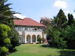 uma grande casa branca com um telhado vermelho em Villa Victoria executive Guest House em Benoni