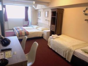 Habitación de hotel con 2 camas y mesa en Hotel Anna en Zandvoort