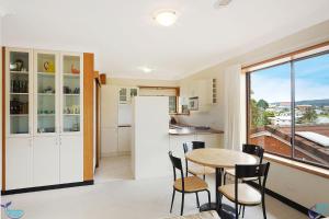 
a kitchen with a table, chairs and a refrigerator at Bayview Unit - Stunning Inlet Views in Narooma

