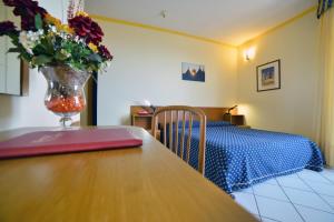 ein Schlafzimmer mit einem Tisch und einer Vase mit Blumen darauf in der Unterkunft Hotel Lo Smeraldo in Cisternino