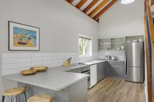 a kitchen with a counter and a stainless steel refrigerator at Bush Retreat With Private Pool in Narooma