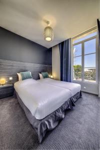 a large bed in a bedroom with a large window at BDX Hôtel - Gare Saint-Jean in Bordeaux