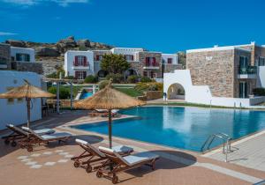 uma vista para uma piscina com cadeiras e guarda-sóis em Naxos Palace Hotel em Stelida